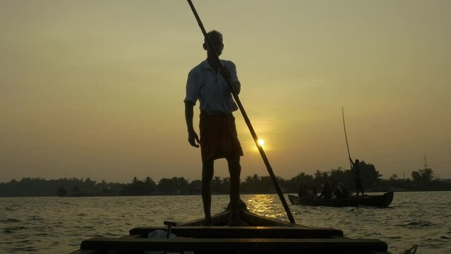 An Indian boatman drives an old boat on the river in the jungle of Kerala on the island of Munroe during sunset. 4k footage.