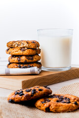 Cookies stacked next to a milk glass on a wood board with cloth