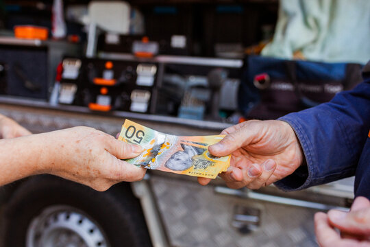 Handing over wad of fifty dollar notes to workman for job