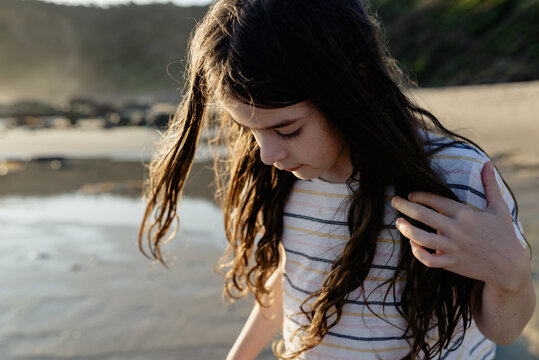 Portrait of a young girl with windswept hair on the beach at sunset