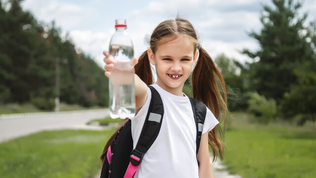 school girl with backpack holding water bottle. Back to school concept. Healthy child.