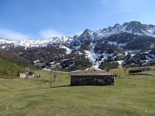 Pradera alpina con cabañas rodeada de montañas nevadas