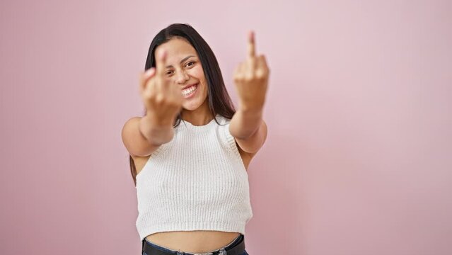 Young beautiful hispanic woman smiling confident doing middle finger gesture over isolated pink background