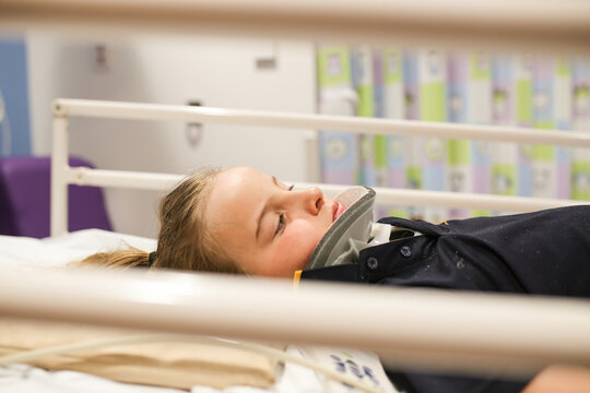 Young girl wearing neck brace in hospital bed