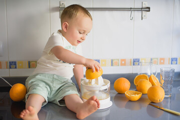 a boy child makes freshly squeezed orange juice on a manual juicer