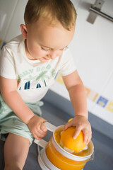 a boy child makes freshly squeezed orange juice on a manual juicer