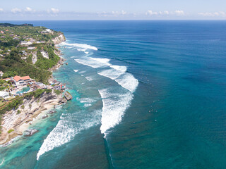 Aerial view of Uluwatu cliff and surf spot with breaking wave, Bukit Peninsula, Bali, Indonesia
