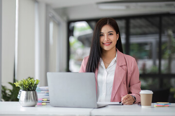 Businesswoman working with laptop computer while having a leisurely cup of coffee at the office in the morning.