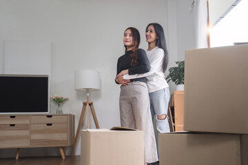 Two young women are carrying cardboard boxes in their room on the day of the move.