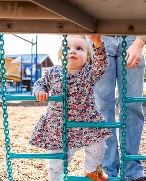 Toddler girl child climbing up metal play equipment at park playground at Rose Point