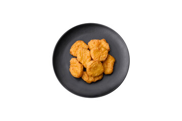 Delicious crispy chicken nuggets with salt and spices on a dark concrete background