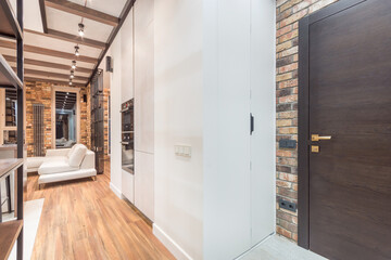 Exclusive interior design of the studio apartment. Finishing with wood and brickwork. The entrance door is made of dark wood.