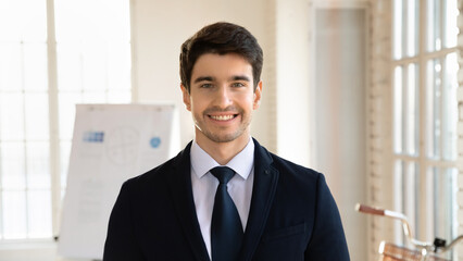 Close up headshot portrait of smiling young Caucasian businessman in formal suit look at camera...
