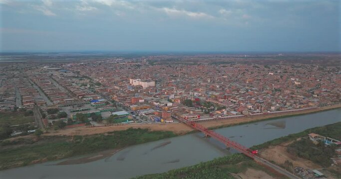 Aerial shot of Tumbes river, bridge and city at sunset. Tropical city at north of Per&uacute;. 