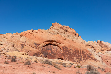 Fototapeta premium Scenic view of white Aztek sandstone rock formations in Petroglyph Canyon along Mouse Tank hiking trail in Valley of Fire State Park in Mojave desert, Nevada, USA. Hot temperature in arid vegetation