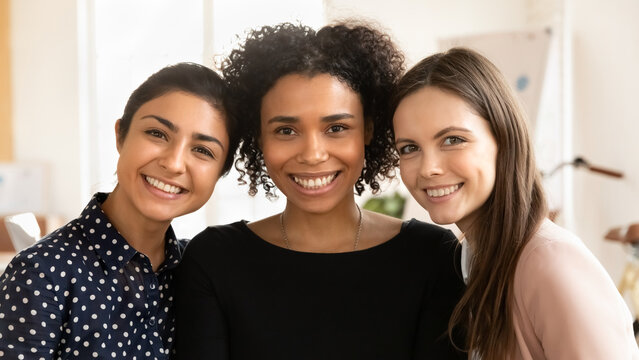 Close Up Portrait Of Smiling Multiethnic Women Friends Hug Embrace Posing In Office Together, Happy Diverse Ethnic Female Colleagues Coworkers Show Friendship At Workplace, Unity And Support At Work