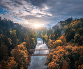 Aerial view of wooden bridge over the river in mountains at foggy autumn morning in Slovenia. Top...