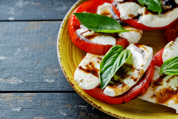 Italian Caprese Salad with sliced tomatoes, mozzarella and basil on dark boards. Copy space