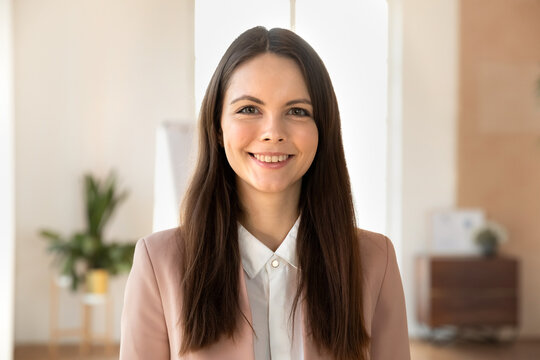 Headshot portrait of smiling Caucasian young female employee posing in modern office, happy successful businesswoman show confidence and optimism, woman worker look at camera, profile picture