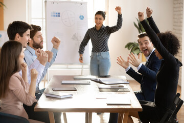 Excited multiracial young businesspeople have fun celebrate shared business win or victory at...