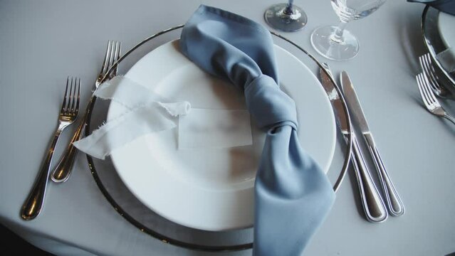 Beautiful plates on the table, a silk blue napkin and white silk ribbon on a plate. Beautiful wedding decor, all decorated in boho style, camera moving slow motion.
