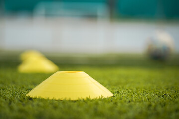 Obstacle cone for speed and moving training on artificial turf ground for football training. Sport equipment object photo. Selectived focus at the front cone. - Powered by Adobe