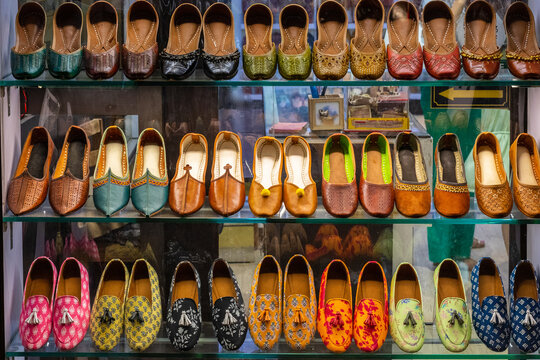 Multicolored shoes, ballerinas, and sandals, placed on shelves in rows.