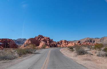Panoramic view of endless winding empty Mouse tank road in Valley of Fire State Park through canyons of red Aztec Sandstone Rock formations and desert vegetation in Mojave desert, Overton, Nevada, USA