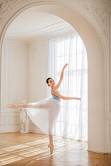 A young ballerina is rehearsing in the studio. happy young ballerina exercising in the barre. Young...