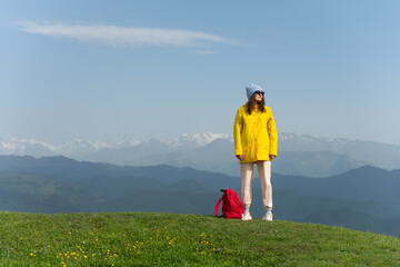 Happy young woman standing on the top of the mountain against mountain range. Successful woman unwinding in the mountains