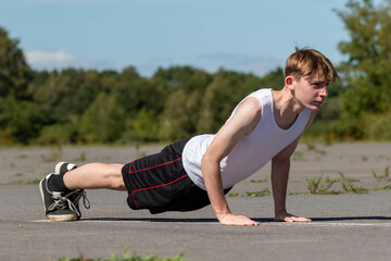 Teenage boy doing push ups outside