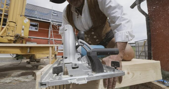 carpenter on a construction site cutting a wooden beam with an electrical saw