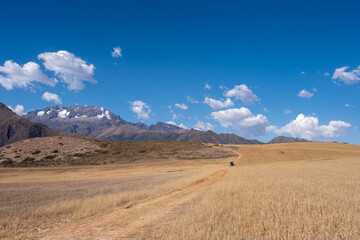 Landscapes of the Andes near the Maras Salt Flats in Peru with a green campervan driving on a dirt road