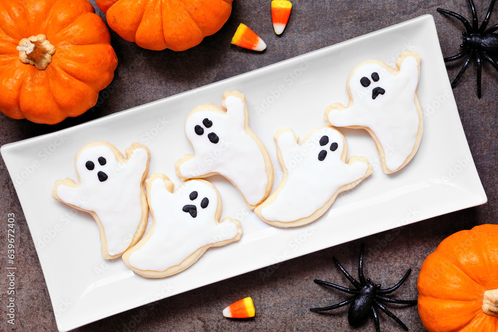 Poster plate of halloween ghost cookies. top down view table scene on a dark background.