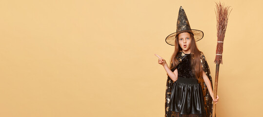 Childhood fascination with magic. Surprised little girl with long hair black cloak clothing with...