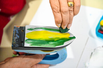 Encaustic wax painting with an iron. Art. Female artist adds colors to the iron.