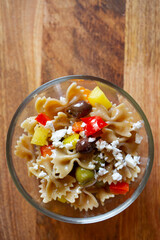 insalata di pasta con feta, peperoni e olive su tagliere di legno