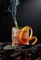 Old-fashioned cocktail  with a burning twig of rosemary.