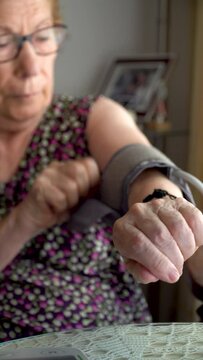 An older woman checks her blood pressure with an electronic blood pressure monitor at home.