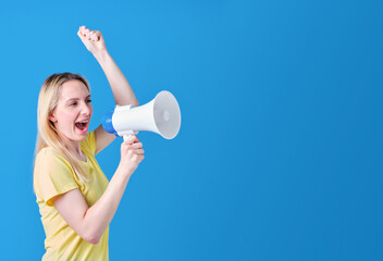 blonde girl in yellow t-shirt with megaphone and raised fist protesting on blue background