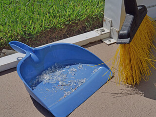 Sweeping shattered glass with sharp edges into the pan with a broom