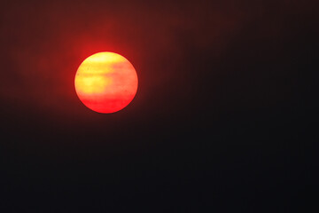 Obraz premium Red round sun covered by smoke from forest wildfire, close up shot, night view, wallpaper design