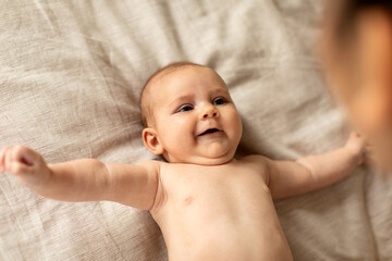 Good morning sunshine. Smiling little baby laying on blanket in cot, ready to wake up, looking at mom and smiling, above view