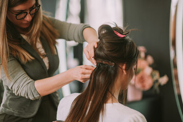 Fototapeta premium Hairstylist tying up clients hair.