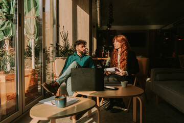 Fototapeta premium Beautiful young business couple talking business while working remotely at the coffee bar