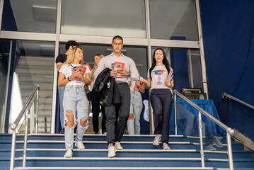 Obraz premium Happy, cheerful students going home after classes, walking downstairs, having a conversation and smiling
