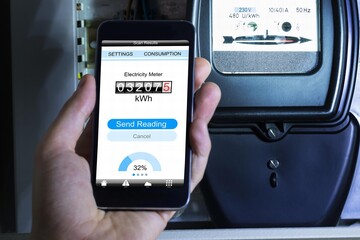 Man's Hand Holding Mobile Phone Showing Electric Meter Reading