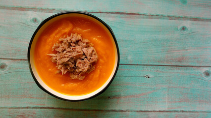 on a blue wooden table a plate with pumpkin cream soup with tuna. view from above . diet