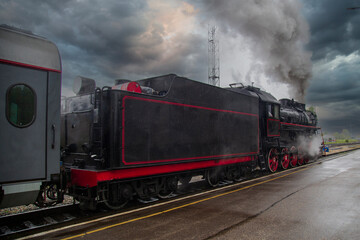 Fototapeta na wymiar An old steam locomotive of the early 20th century on the railway track.