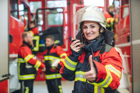 Beautiful fire fighter woman with her helmet in hand standing in the firehouse